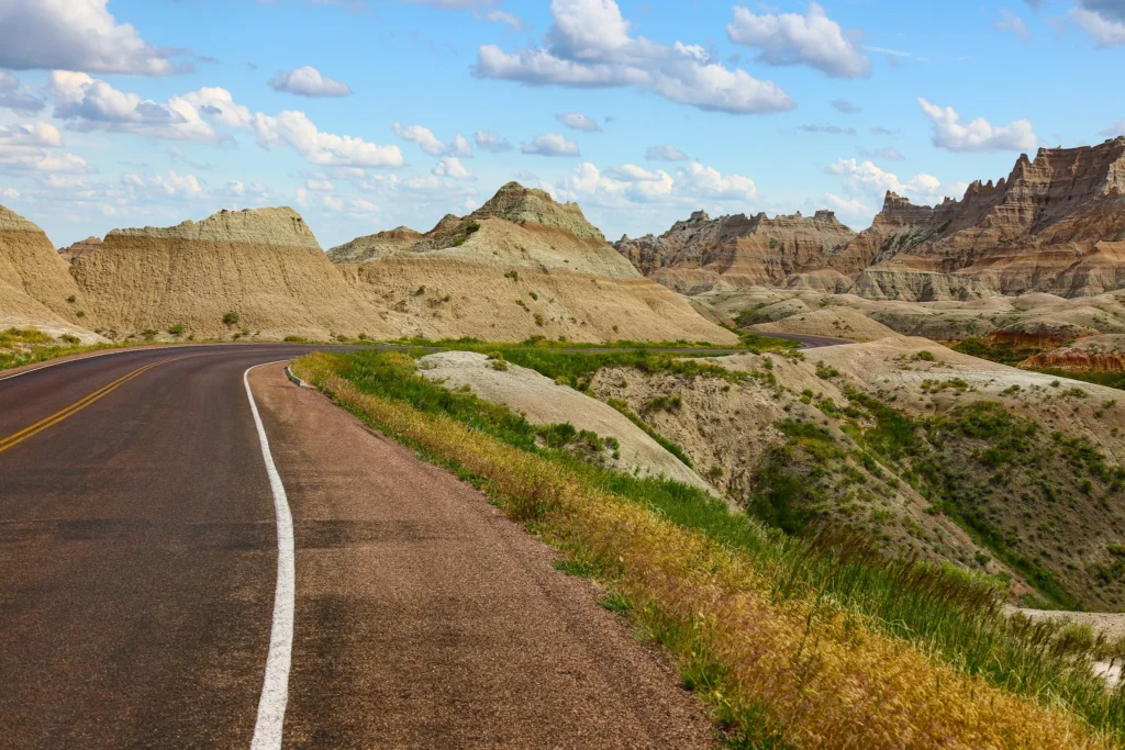 Titelbild Roadtrip mit Kindern – leere Straße durch die Badlands in den USA unter blauem Himmel.