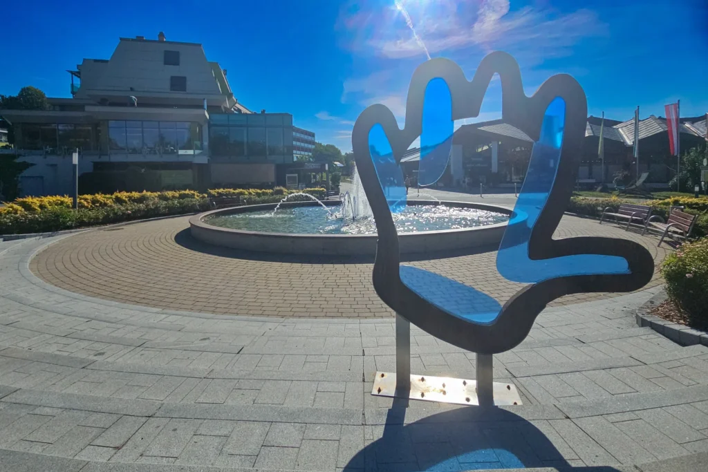 Eingangsbereich der Therme Loipersdorf mit Brunnen und Hand-Skulptur bei Sonnenschein