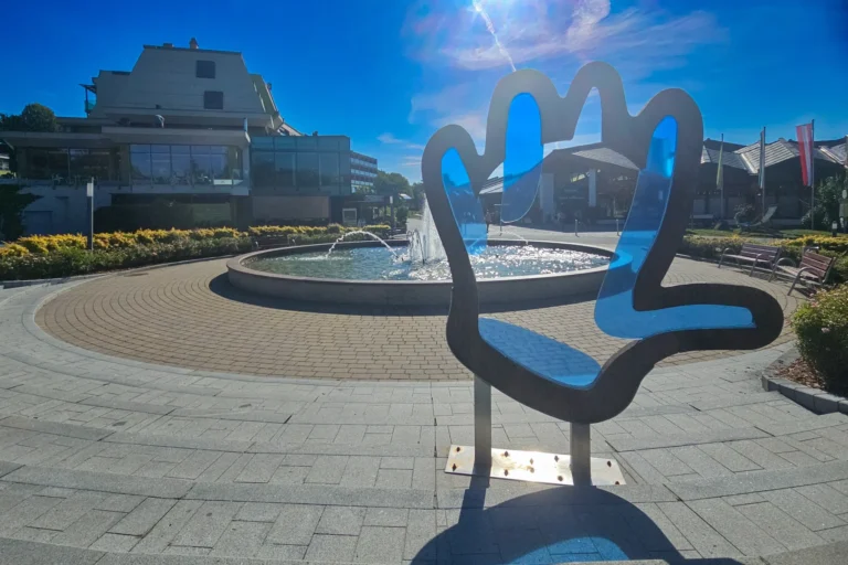 Eingangsbereich der Therme Loipersdorf mit Brunnen und Hand-Skulptur bei Sonnenschein