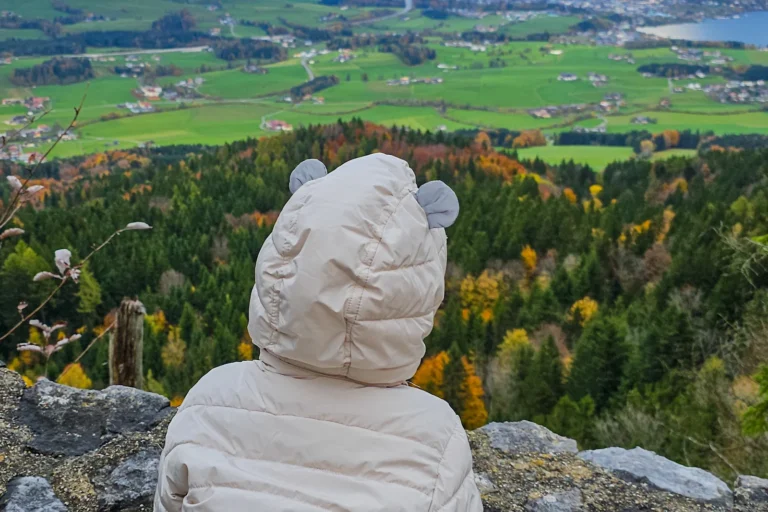 Kind blickt von der Burgruine Wartenfels auf den Wolfgangsee und das Salzkammergut im Herbst.