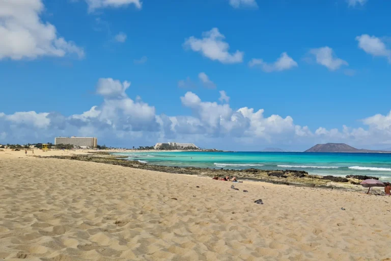 Strand von Corralejo auf Fuerteventura mit hellem Sand, türkisblauem Meer und Blick auf Lobos.