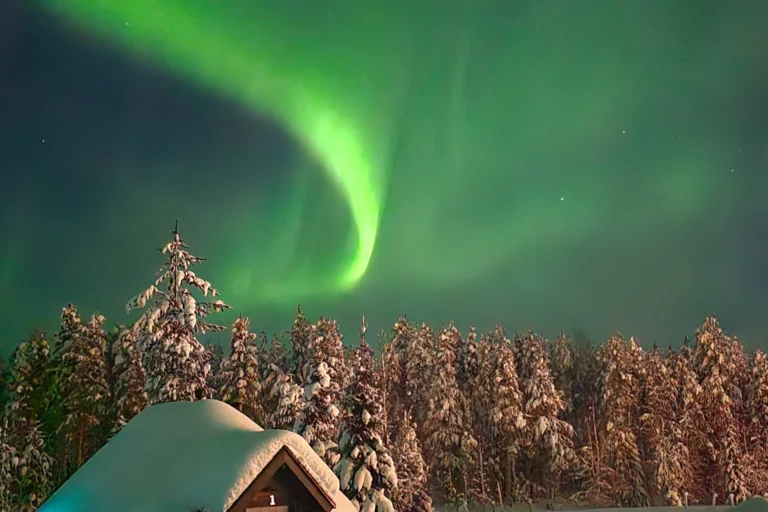 Grüne Nordlichter am Himmel über einem Glasiglu in Levi in Lappland