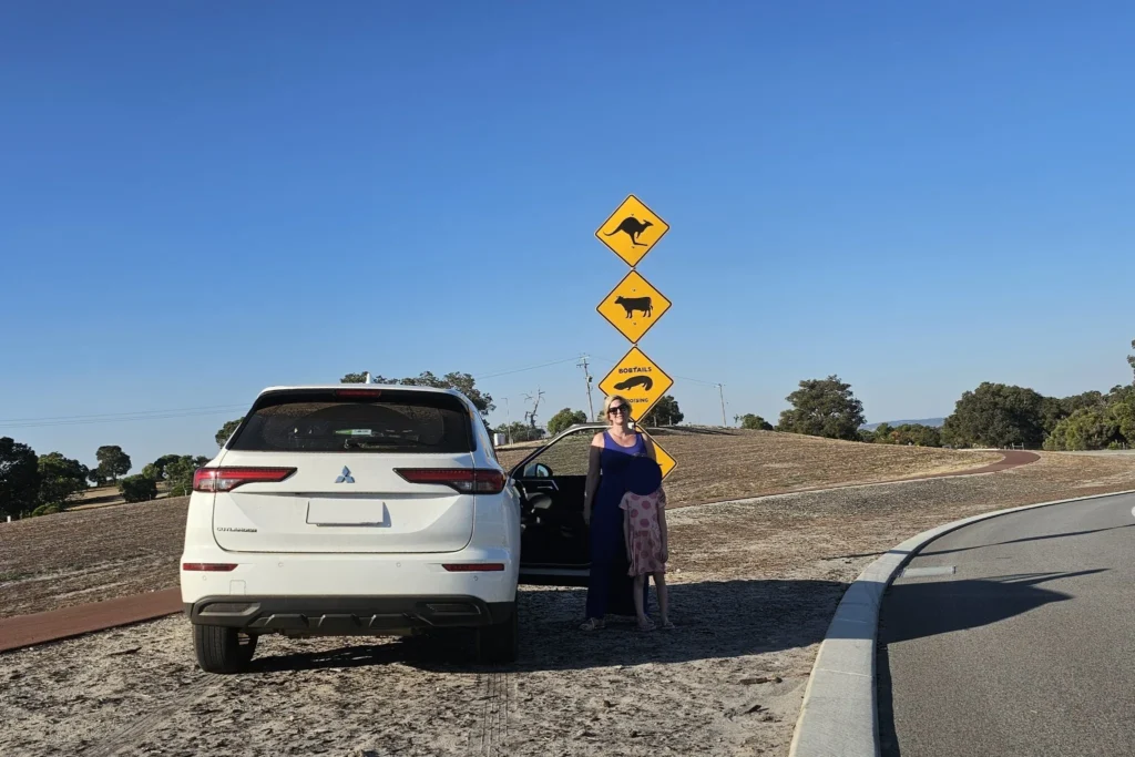 Mutter und Tochter machen ein Foto vor ikonischen Känguru- und Wildtier-Warnschildern während eines Roadtrips durch Australien.