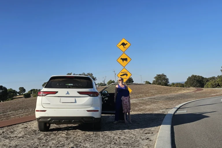 Mutter und Tochter machen ein Foto vor ikonischen Känguru- und Wildtier-Warnschildern während eines Roadtrips durch Australien.